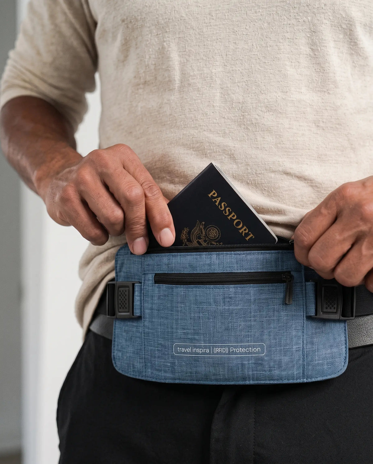 A person slipping a passport into a blue Travel Inspira RFID-blocking neck pouch/waist money belt worn around the waist.